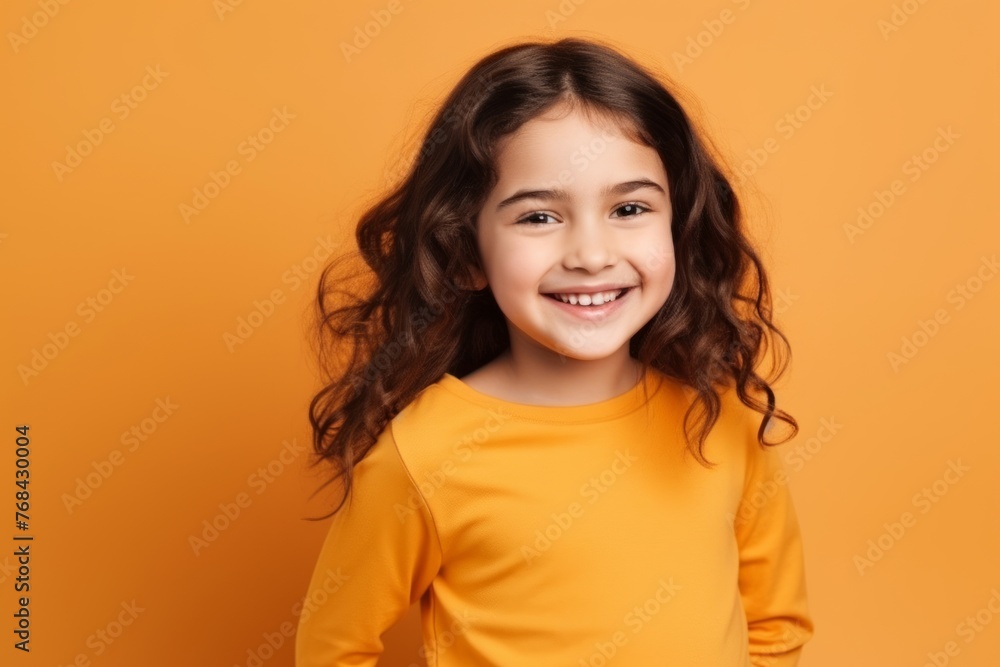 Portrait of a cute little girl smiling at camera over orange background Portrait of a cute little girl smiling at camera over orange background
