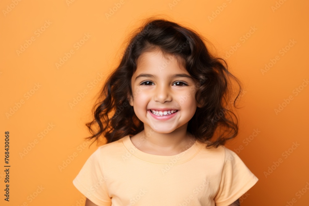 Portrait of a happy little girl with long curly hair on orange background Portrait of a happy little girl with long curly hair on orange background