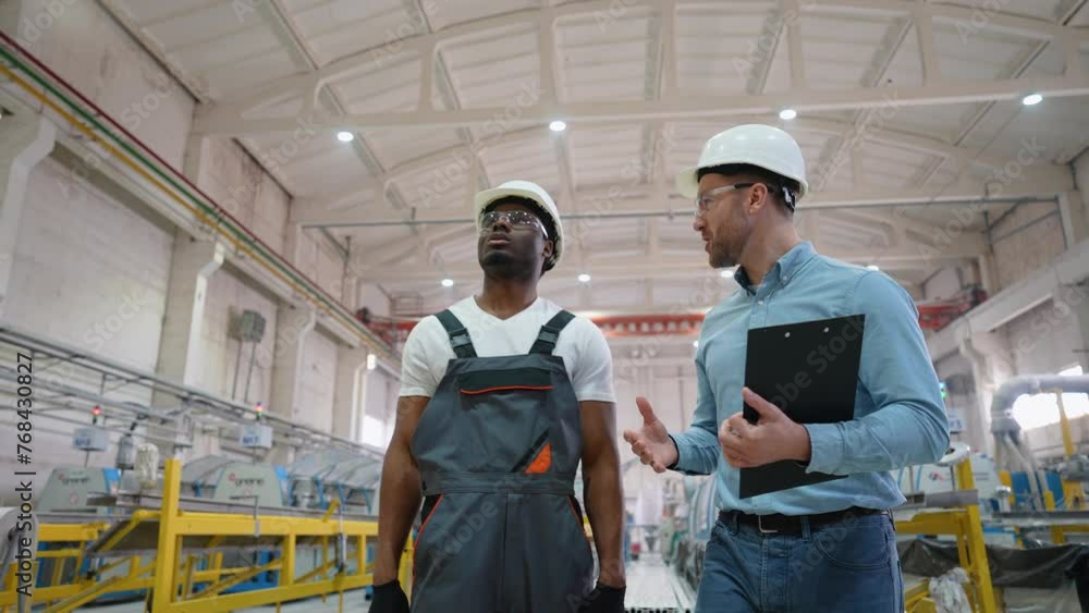 Supervisor and manual worker walking and discussing manufacture on PVC factory