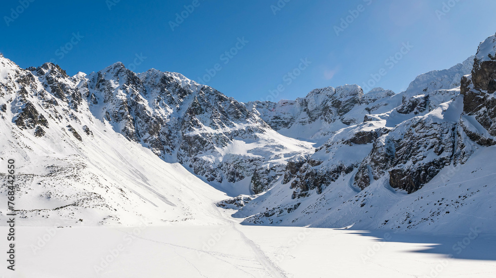 Szczyty otaczające Czarny Staw Gąsienicowy w polskich Tatrach sfotografowane w słoneczny zimowy dzień. - obrazy, fototapety, plakaty 