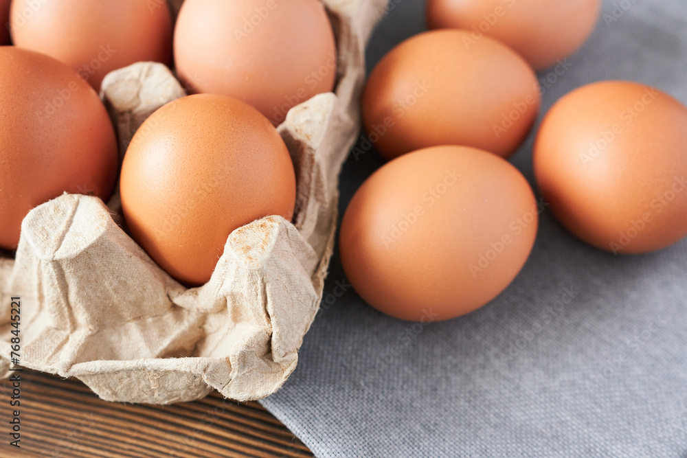 Fresh chicken eggs in carton box on wooden table, closeup Fresh chicken eggs in carton box on wooden table, closeup