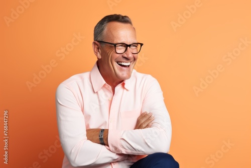 Portrait of happy senior man in glasses and shirt on orange background