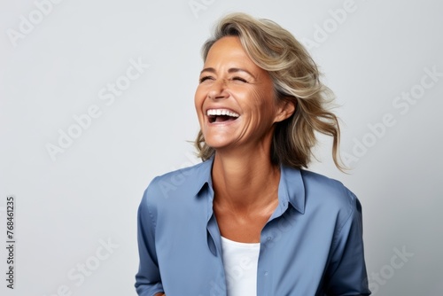 Closeup portrait of a happy senior business woman laughing against grey background