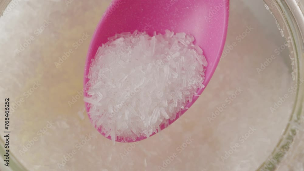 Close-up of a pink spoon scooping white monosodium glutamate crystals Close-up of a pink spoon scooping white monosodium glutamate crystals