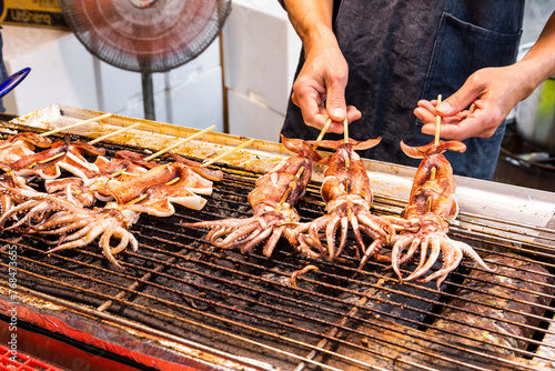 Close-up of the vendors are grilling squid skewers in the night market of Taiwan. 