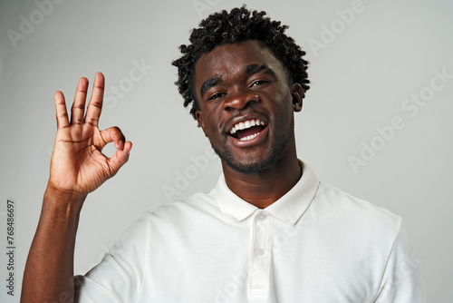 African Man in White Shirt Making Peace Sign against Gray Background
