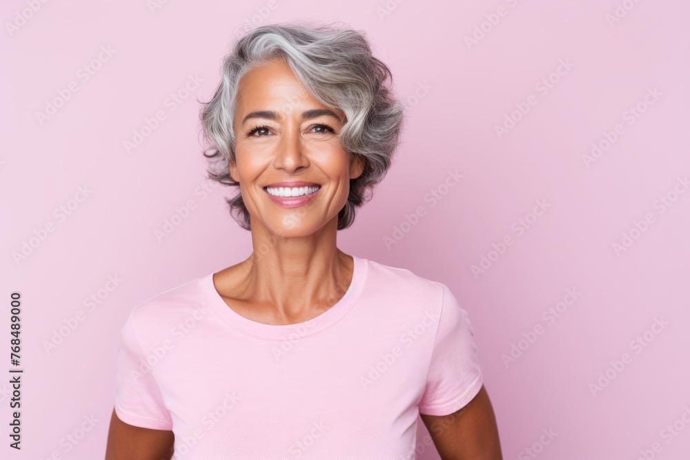 Beautiful mature woman looking at camera and smiling while standing against pink background Beautiful mature woman looking at camera and smiling while standing against pink background