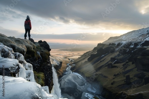 person overlooking a valley from atop waterfall ice
