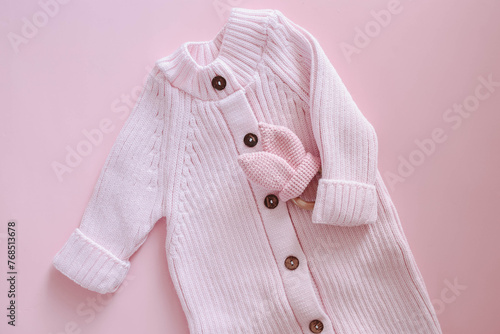 Knitted jumpsuit for a newborn on a pink background. Outerwear for toddlers for walks in autumn or spring