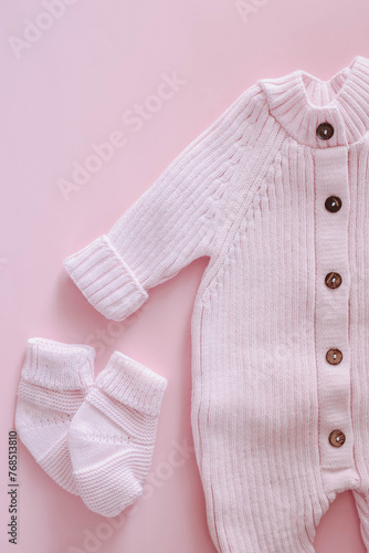 Knitted jumpsuit for a newborn on a pink background. Outerwear for toddlers for walks in autumn or spring