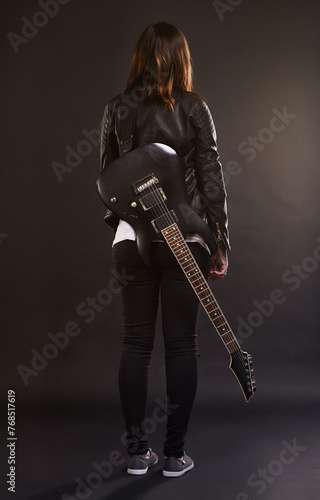 Woman, guitar and fashion for musical instrument, sound and trendy for retro and style on dark background. Young person or musician for creative, funky and edgy for bold with leather jacket for rock
