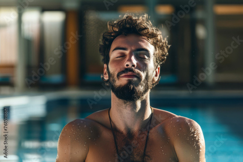 Portrait of a handsome young man with closed eyes shirtless in a swimming pool. Wellness concept.