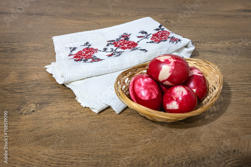 Traditional Romanian red Easter eggs decorated with leaves and boiled in onion peels on a wooden table