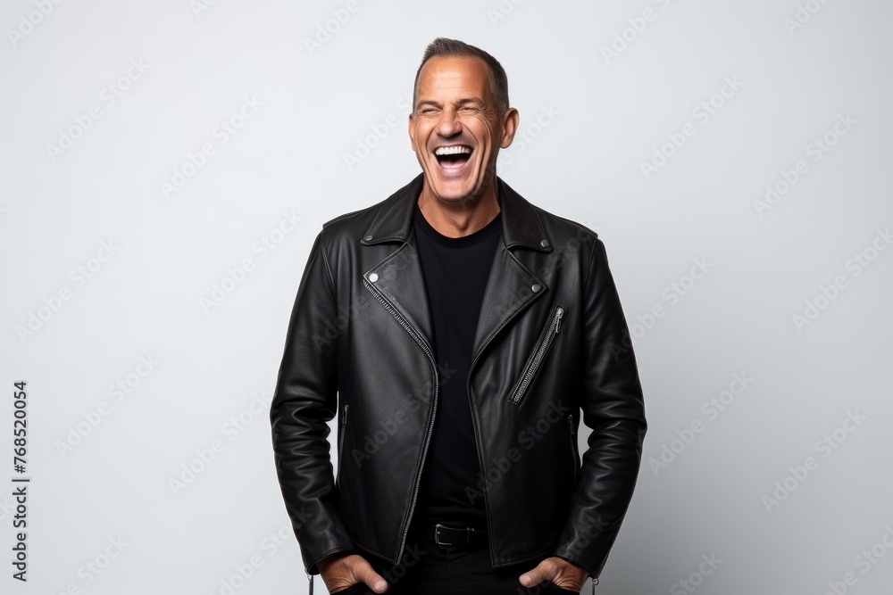 Portrait of a middle-aged man with a leather jacket laughing on a gray background Portrait of a middle-aged man with a leather jacket laughing on a gray background