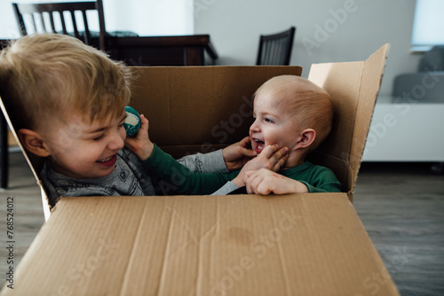 Close up of two young boys playing wildly in a cardboard box photo