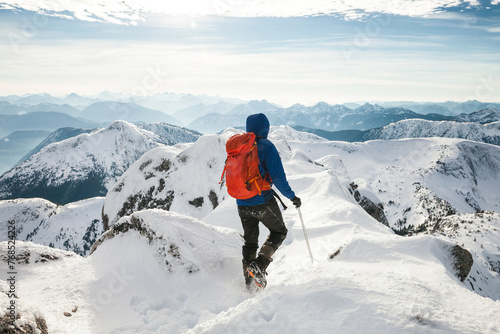 A mountaineer carefully walks across a mountain ridge