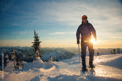 mountain climber hiking using snowshoes at sunset photo