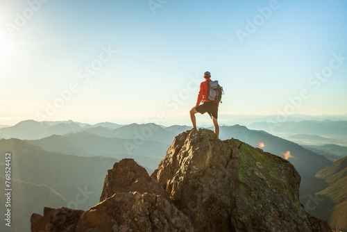 successful man stands on mountain summit at sunset
