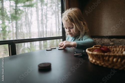 Child at camper table eating chocolate sandwich cookies as snack