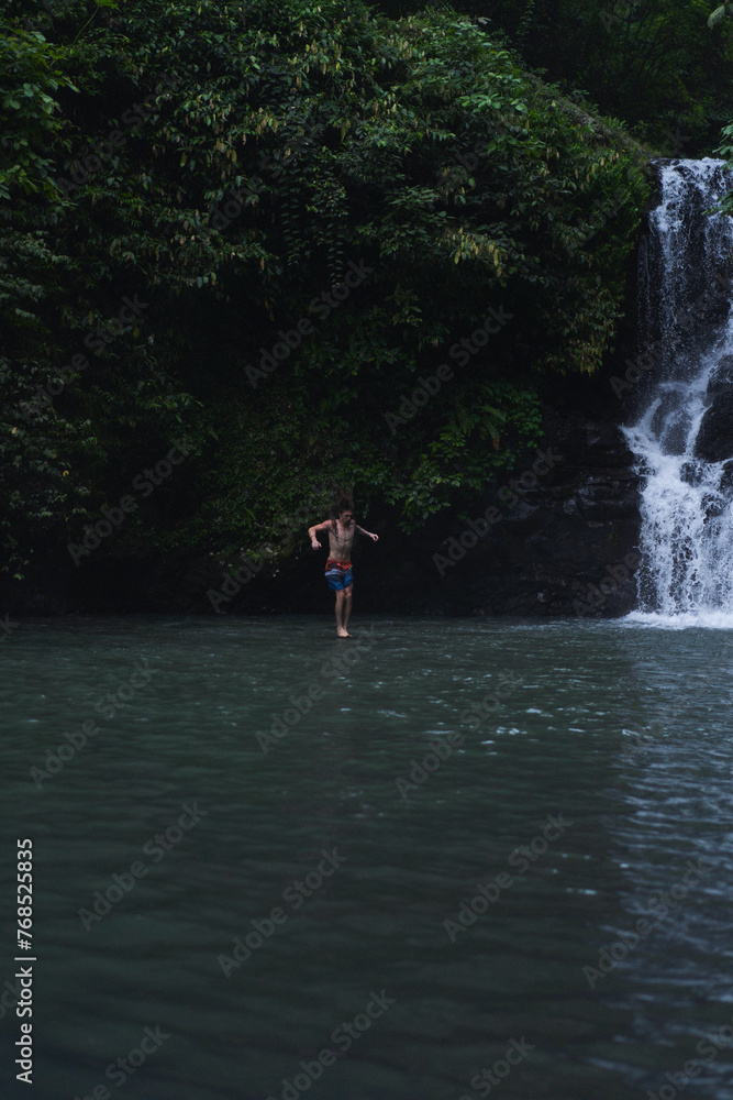Man jumps from a cliff into the Alin-Alin waterfall. Bali Man jumps from a cliff into the Alin-Alin waterfall. Bali