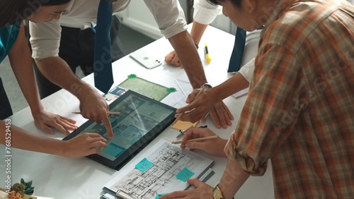 Close up of smart business team hand working together to plan design while looking at project plan from tablet and discussing about blueprint and building construction at meeting table. Alimentation.