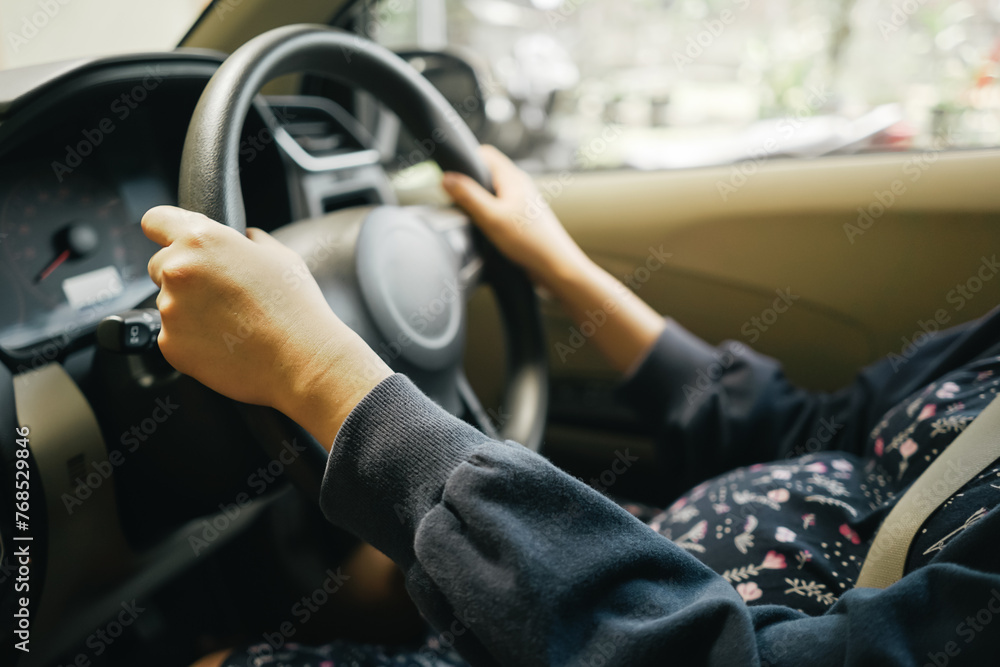 Cockpit view pregnant woman holding steering wheel when driving a car Cockpit view pregnant woman holding steering wheel when driving a car