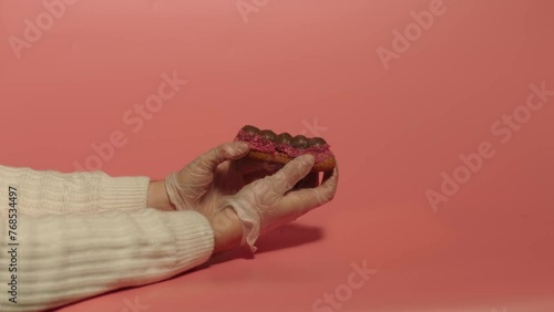 Hands braking eclair in two pieces. Pink background. Cheneese desert. Food. 