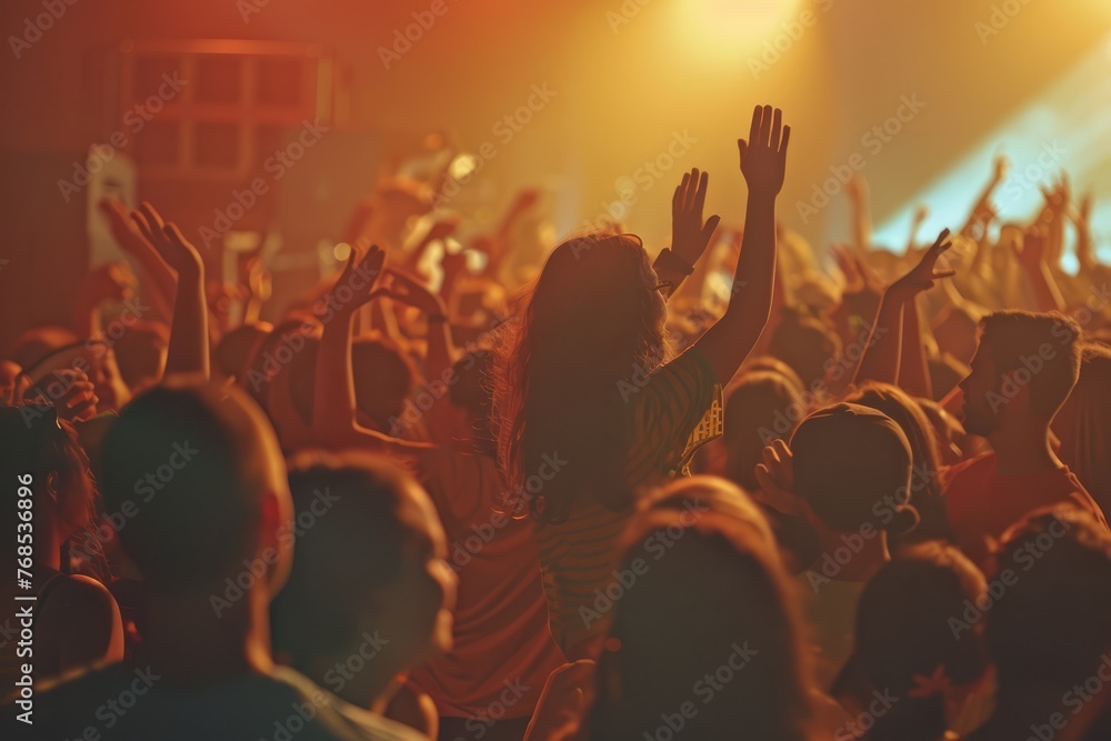 A dynamic crowd of people enthusiastically raising their hands in the air during a concert event