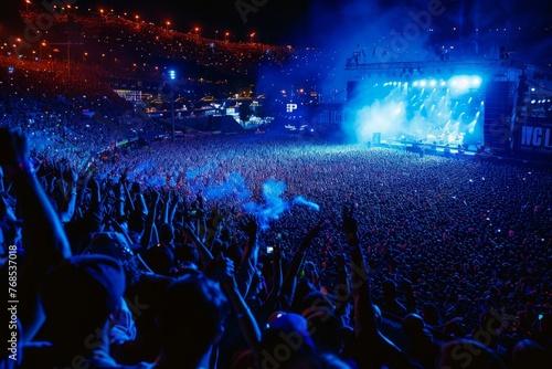 A large group of people enjoying a concert, illuminated by stage lights and music, creating an electrifying atmosphere
