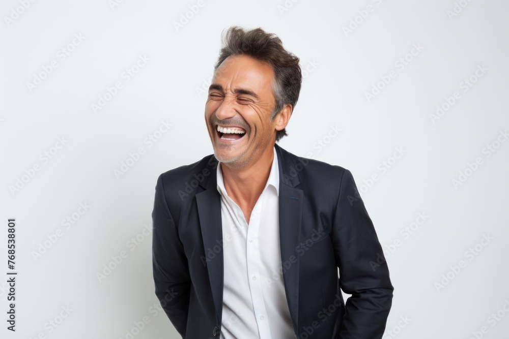 Portrait of a happy mature businessman laughing and looking at camera on grey background Portrait of a happy mature businessman laughing and looking at camera on grey background