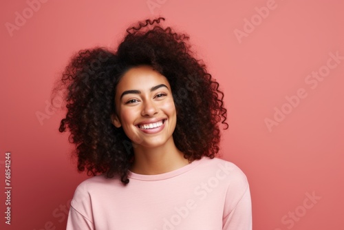 Portrait of a beautiful young african american woman with curly hair on pink background