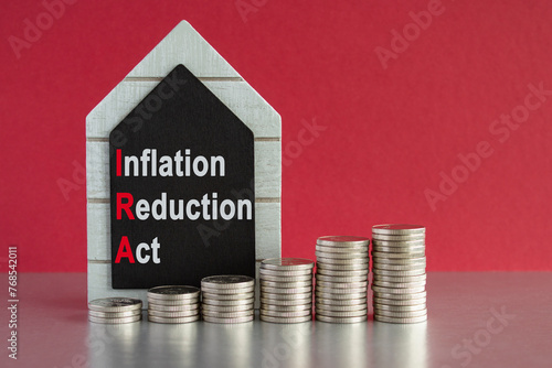 IRA inflation reduction act symbol. Concept words inflation reduction act on a black board. Silver coins arranged in a graph in front. Beautiful red background.  photo