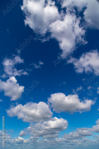 White cumulus clouds on a clear blue sky.