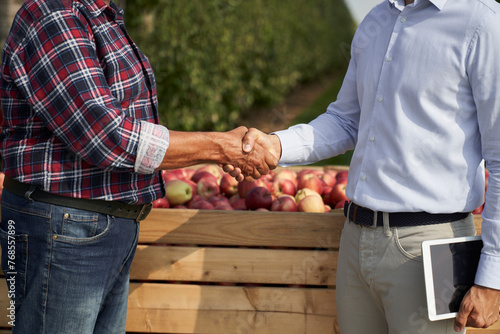 Successful transaction between senior farmer and sales representative on apple orchard photo