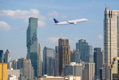 Flying passenger plane in the sky above the city and skyscrapers of the metropolis. The concept of traveling to a modern developed country.