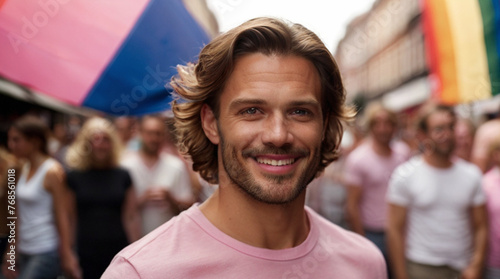 Portrait of young man on the street during pride parade with rainbow LGBT flag in the background