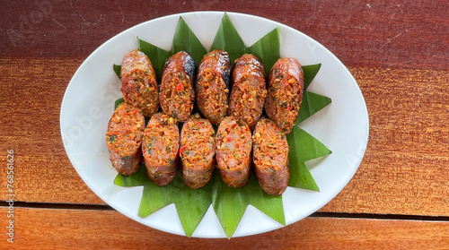 Thai sausage or sai oua. Northern Thai food menu over plate on wooden table background. thaifood concept © Shinonome Studio