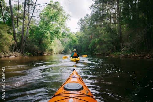 single kayaker paddling downstream with forested banks on both sides