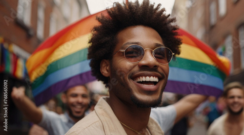 Portrait of Afro American man on the street during pride parade with rainbow LGBT flag in the background