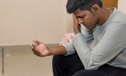 young sad and depressed Indian man looking the ring concept of breakup photo