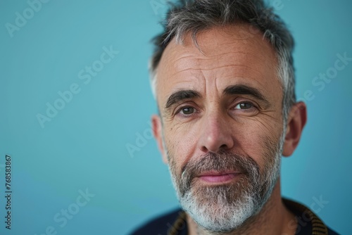 Portrait of senior man with grey beard and mustache against blue background