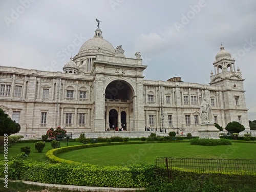 The grand Victoria Memorial Hall stands under a dramatic cloud-filled sky, showing off its exquisite colonial architecture with its towering domes and intricate stonework.