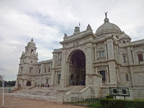 The grand Victoria Memorial Hall stands under a dramatic cloud-filled sky, showing off its exquisite colonial architecture with its towering domes and intricate stonework. © sumit