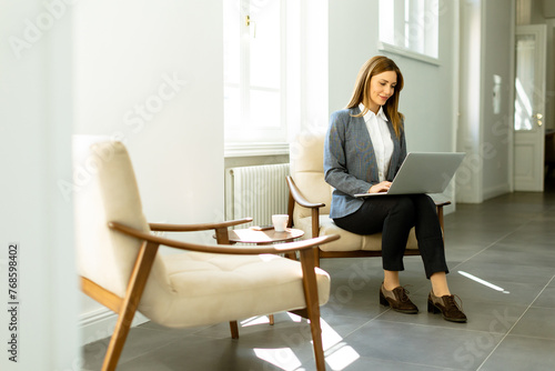 Serene afternoon at work: a professional woman focuses intently on her laptop in a sunlit room