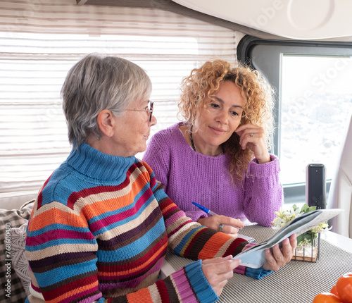 Two caucasian women mother and daughter or friends sitting inside camper van motor home planning trip. Lifestyle and travel modern people, vacation journey concept photo