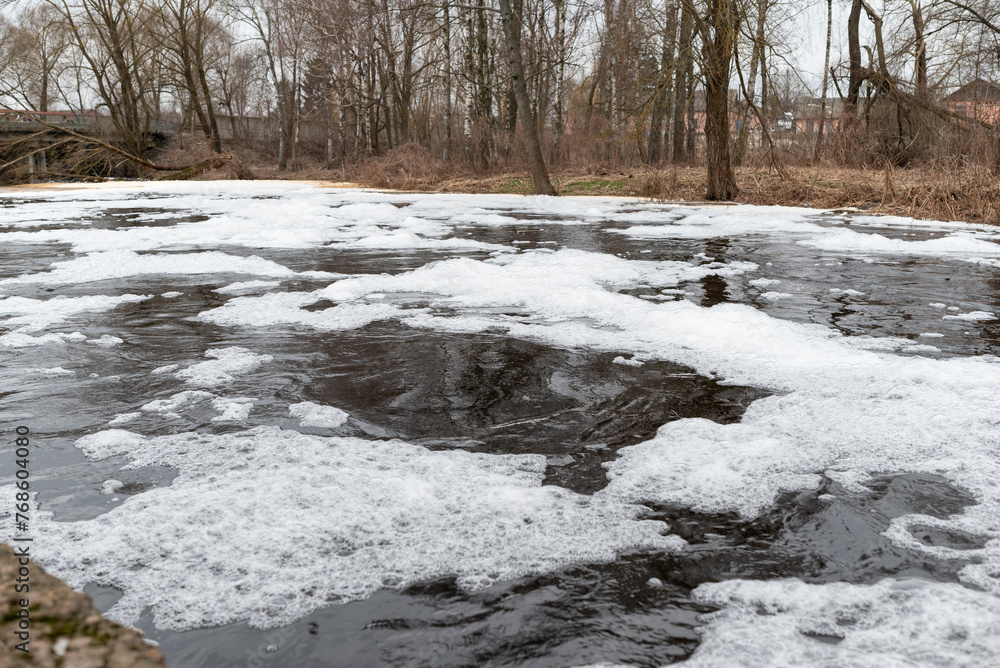 Foaming unclean water in a small river. Concept of pollution and water contamination, spring or autumn nature view on the background Foaming unclean water in a small river. Concept of pollution and water contamination, spring or autumn nature view on the background