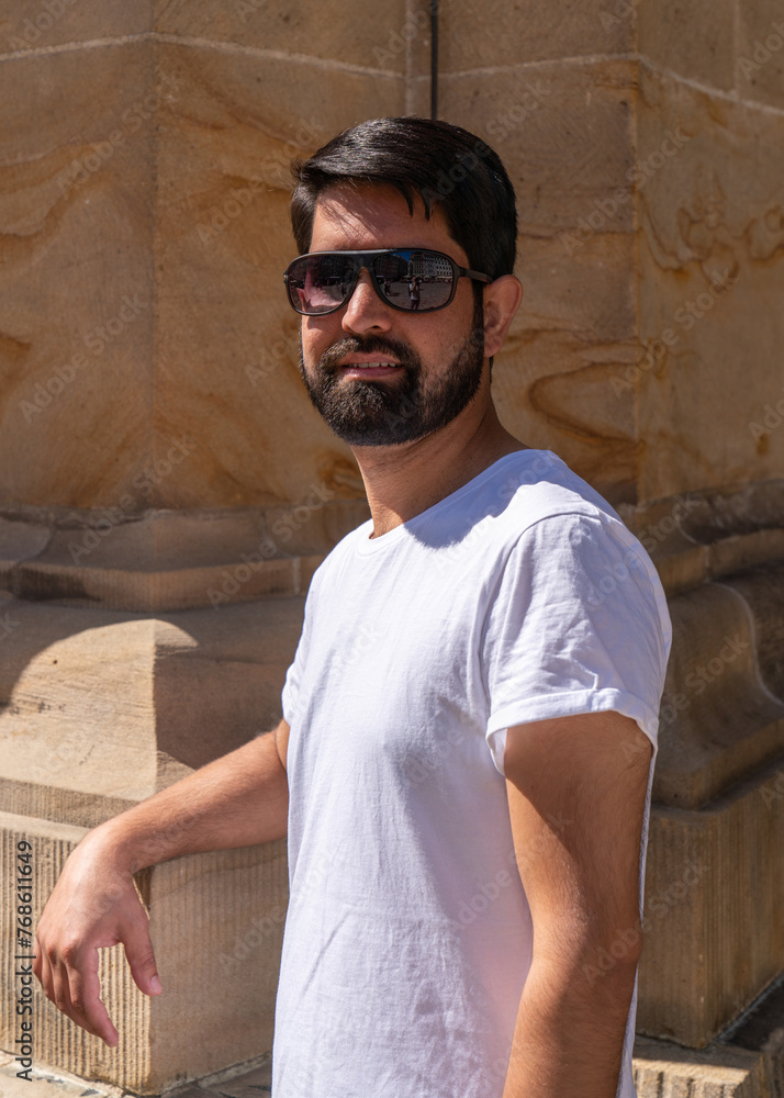 Close-up portrait of a modern Pakistani man with a dark beard, light clothes and sunglasses. Close-up portrait of a modern Pakistani man with a dark beard, light clothes and sunglasses.