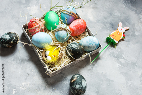 Happy Easter. Natural dyed colorful eggs in paper tray on concrete board in rustic style.
