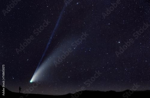 Cometa che passa vicina all'orizzonte, di notte, con un fotografo che esegue una fotografia