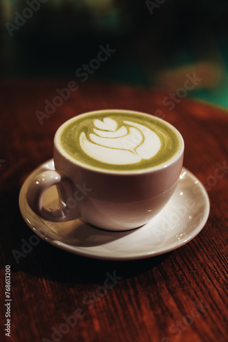 A cup of Japanese matcha green tea and milky foam on a wooden table